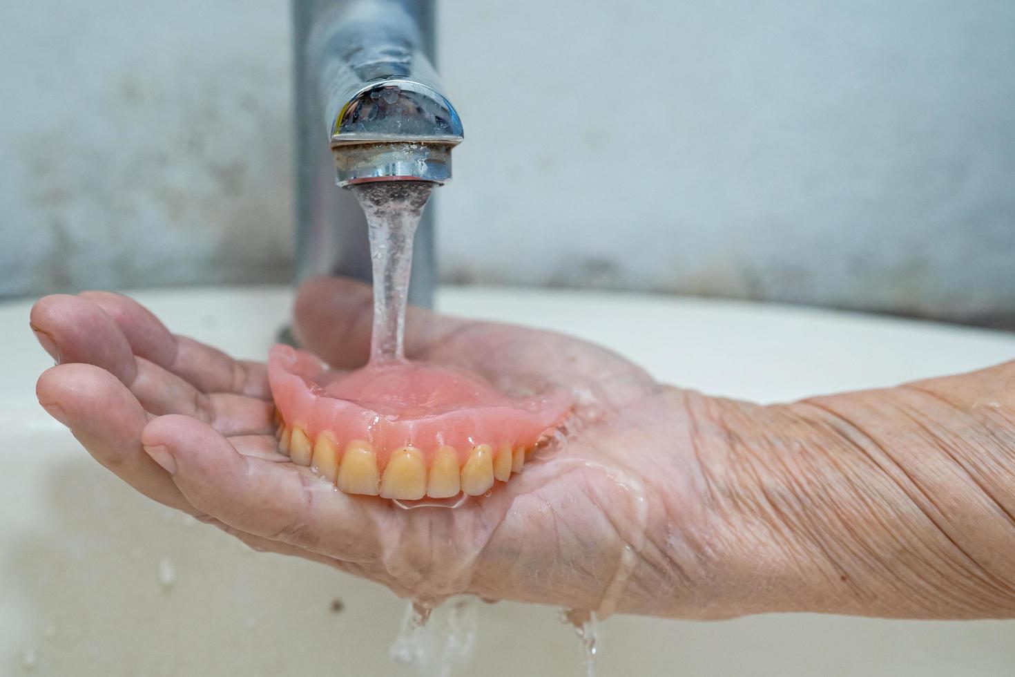 Senior asiatique ou vieille femme âgée patient tenant une prothèse partielle de dents de remplacement photo