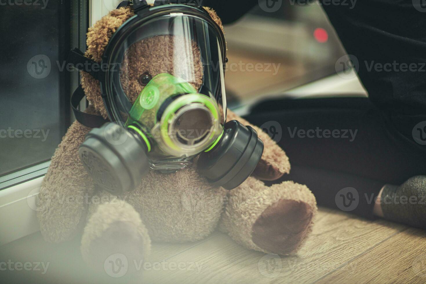 enfant avec nounours ours portant gaz masque à la recherche en dehors le la fenêtre. photo