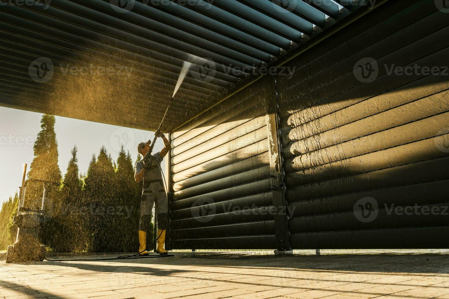 Hommes avec pression machine à laver nettoyage le sien Résidentiel aluminium abri d'auto pergola photo