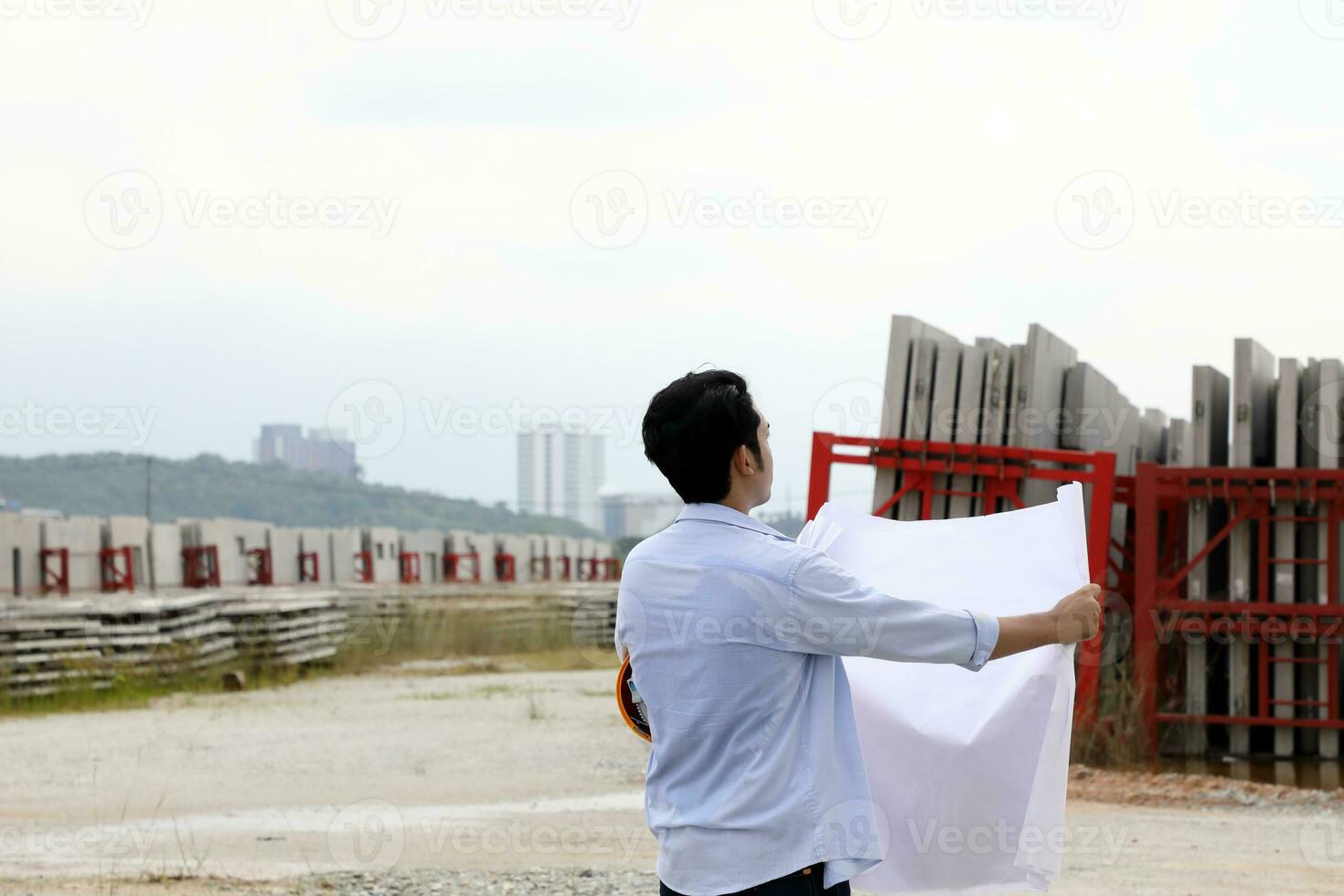 asiatique homme malais ouvrier ingénieur la gestion difficile sécurité chapeau casque à construction site en train de lire voyant plan bleu ciel photo