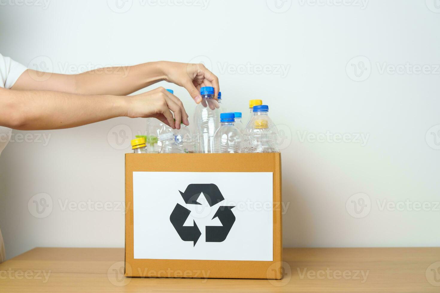 bénévole garder Plastique bouteille dans papier boîte à Accueil ou bureau. main tri recycler ordures. écologie, environnemental, pollution, disposer recyclage, déchets la gestion et poubelle séparation concept photo