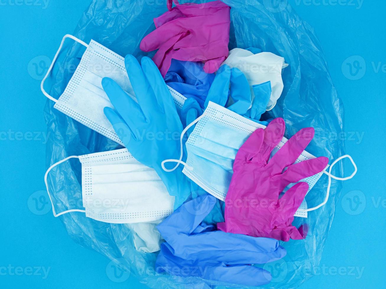 Masques de déchets de coronavirus pandémique médicale et gants en latex dans un sac poubelle sur fond bleu photo