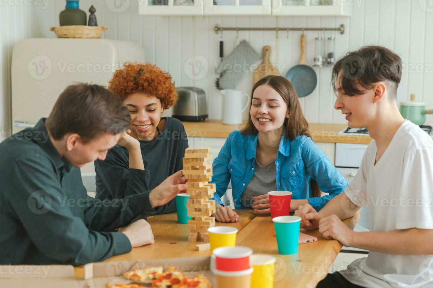 Accueil faire la fête. copains dépenses temps ensemble en jouant dans planche Jeu crash en bois la tour à maison. content diverse groupe ayant amusement ensemble intérieur. mixte course Jeune copains meilleur copains profiter fin de semaine. photo