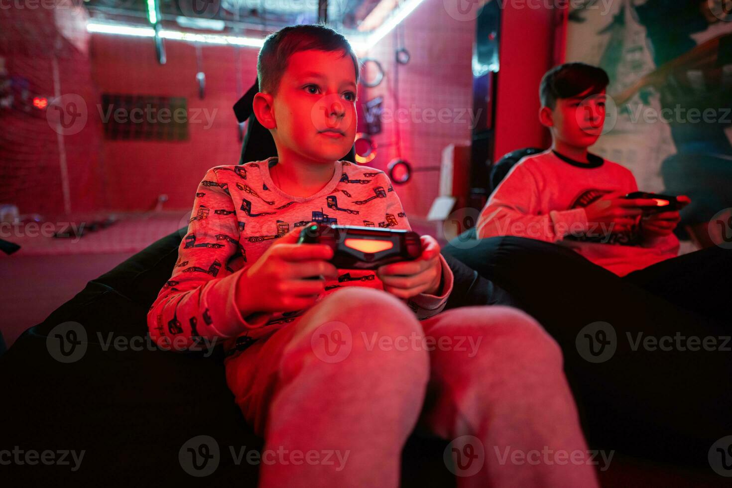 deux garçons les joueurs jouer manette de jeu vidéo Jeu console dans rouge jeu chambre. photo