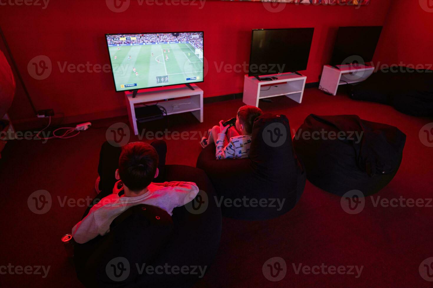 deux garçons les joueurs jouer Football manette de jeu vidéo Jeu console dans rouge jeu chambre. photo