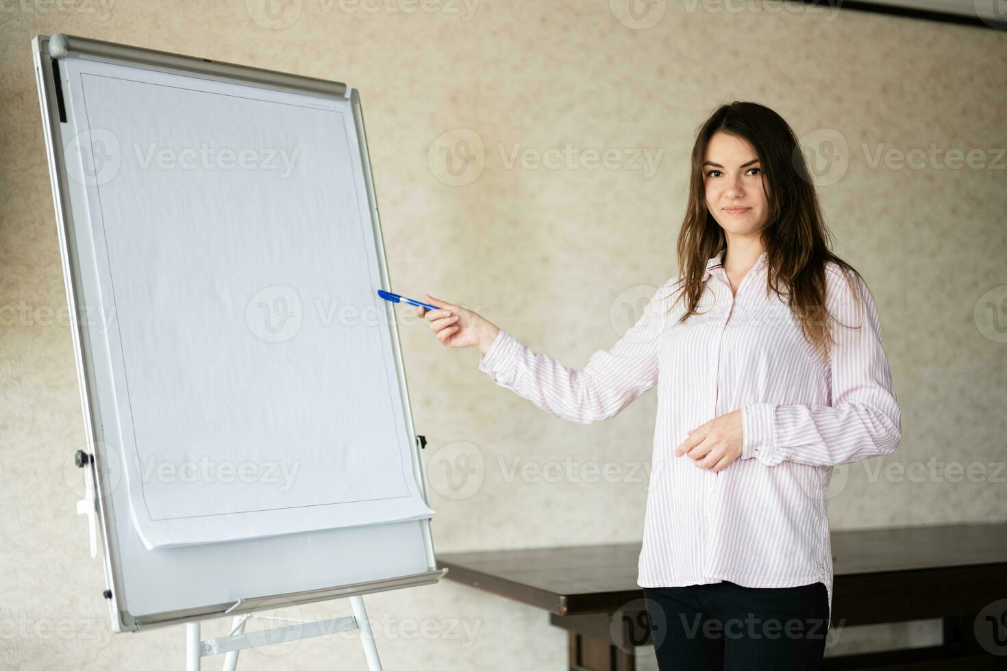 concentré Jeune caucasien orateur femme entraîneur spectacle sur blanc conseil, en train de préparer ou donnant éducatif conférence. femelle équipe chef expliquant projet idées. photo