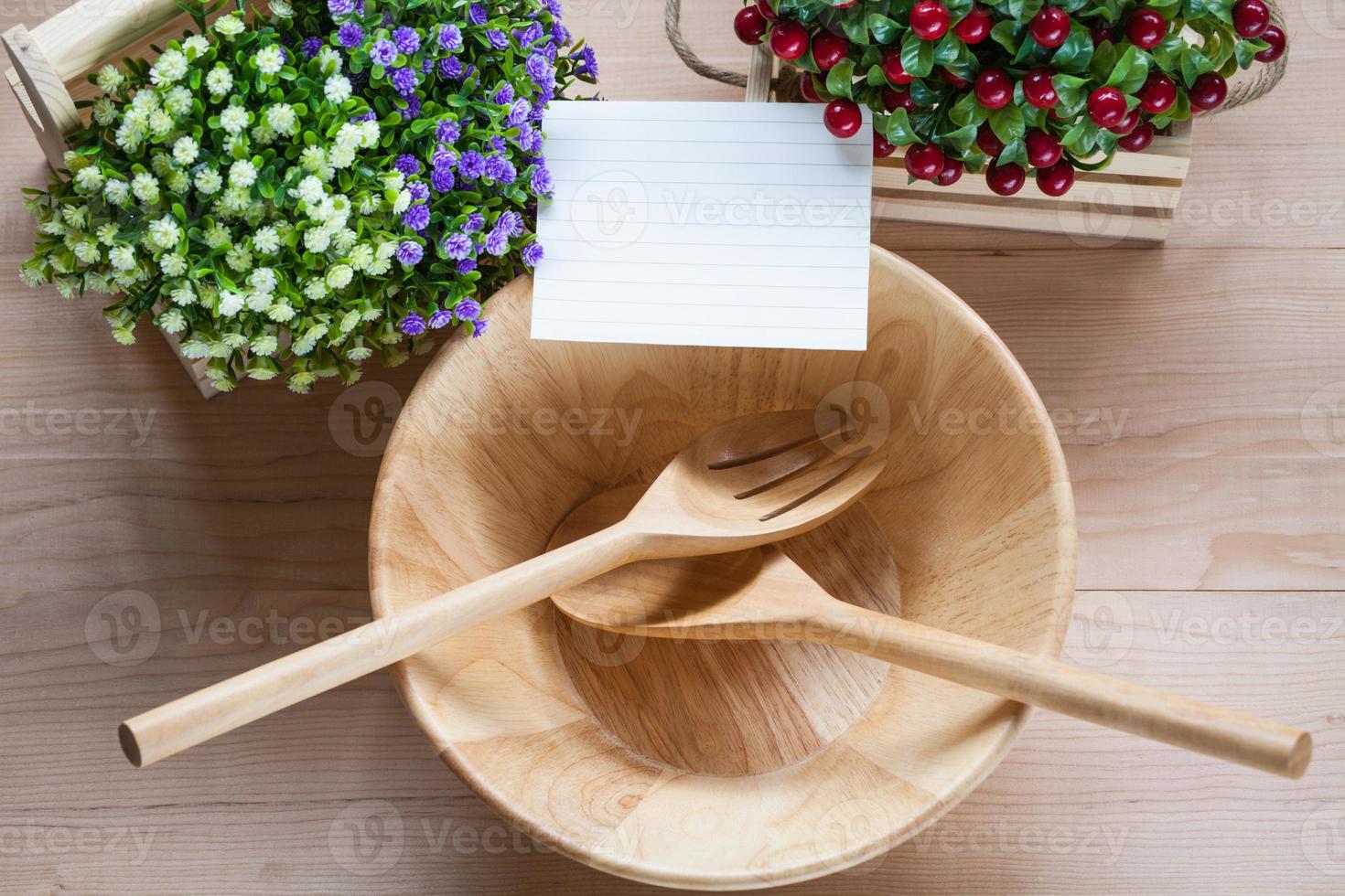 Bol en bois avec cuillère fourchette et notes de papier sur fond de bois photo