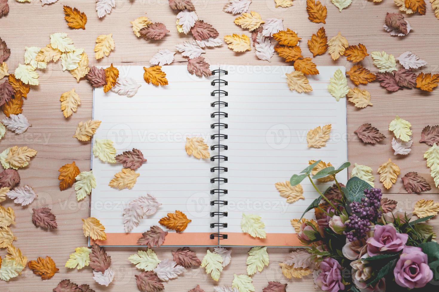 cahier à spirale avec des feuilles d'érable sur fond de bois photo