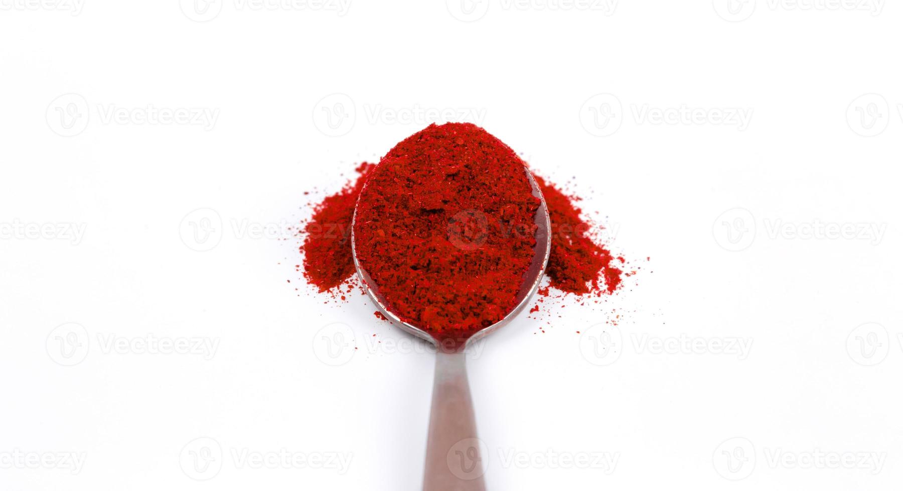 Piment rouge en poudre dans une cuillère en métal sur fond blanc photo