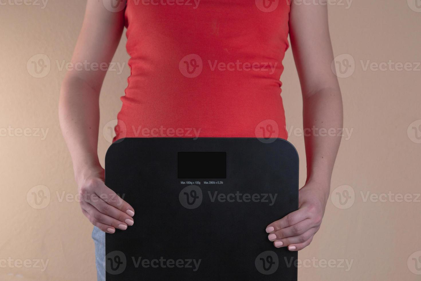 Une vue rapprochée du ventre d'une femme enceinte en rouge qui tient des échelles dans ses mains photo