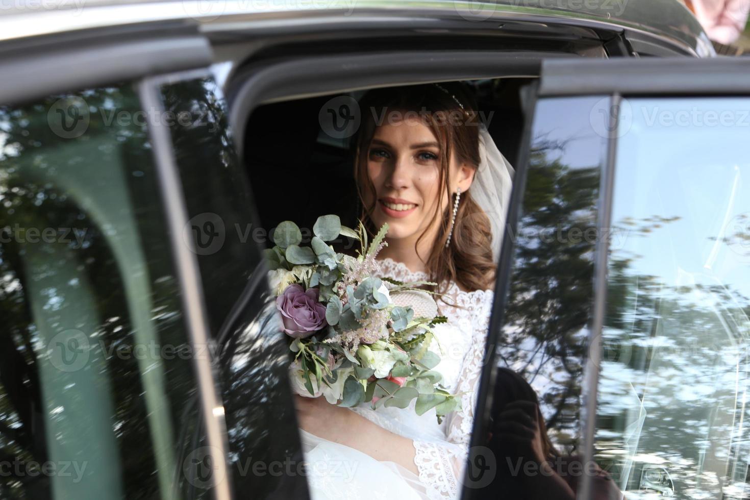 photo de mariage de la mariée assise dans la voiture avec un bouquet de fleurs