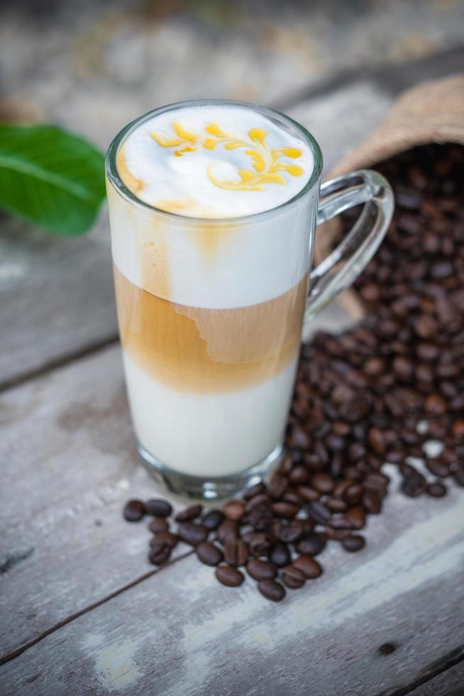 Café au caramel chaud en verre avec des grains de café photo