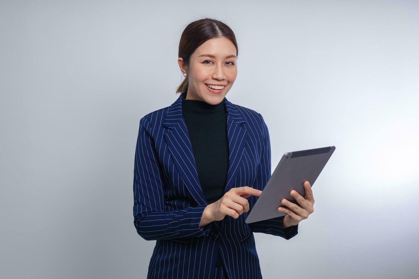 Asian woman smiling and holding digital tablet debout sur fond blanc photo