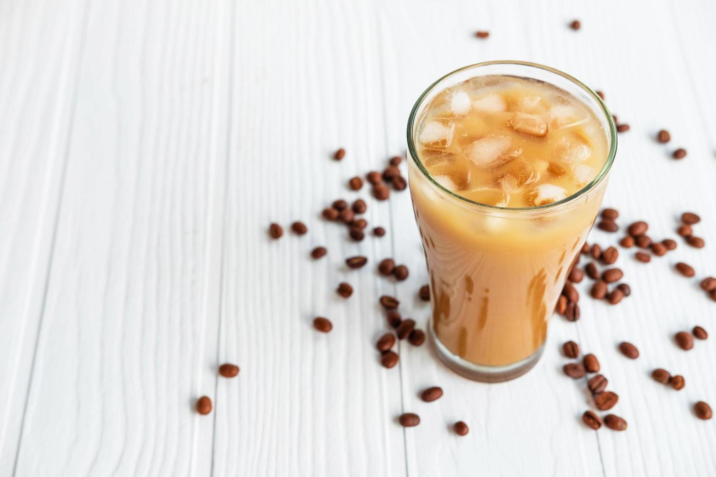 Café glacé dans un verre sur un fond en bois blanc photo