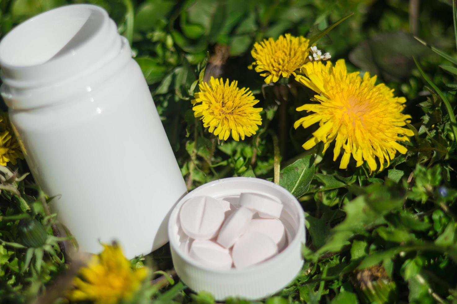 pilules blanches dans l'herbe avec des fleurs photo