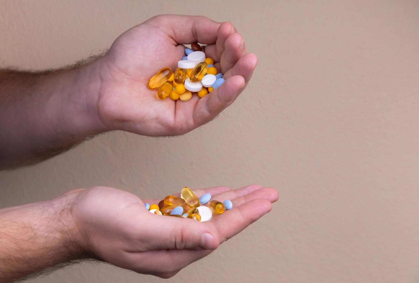 Un tas de pilules multicolores dans les mains d'un homme photo