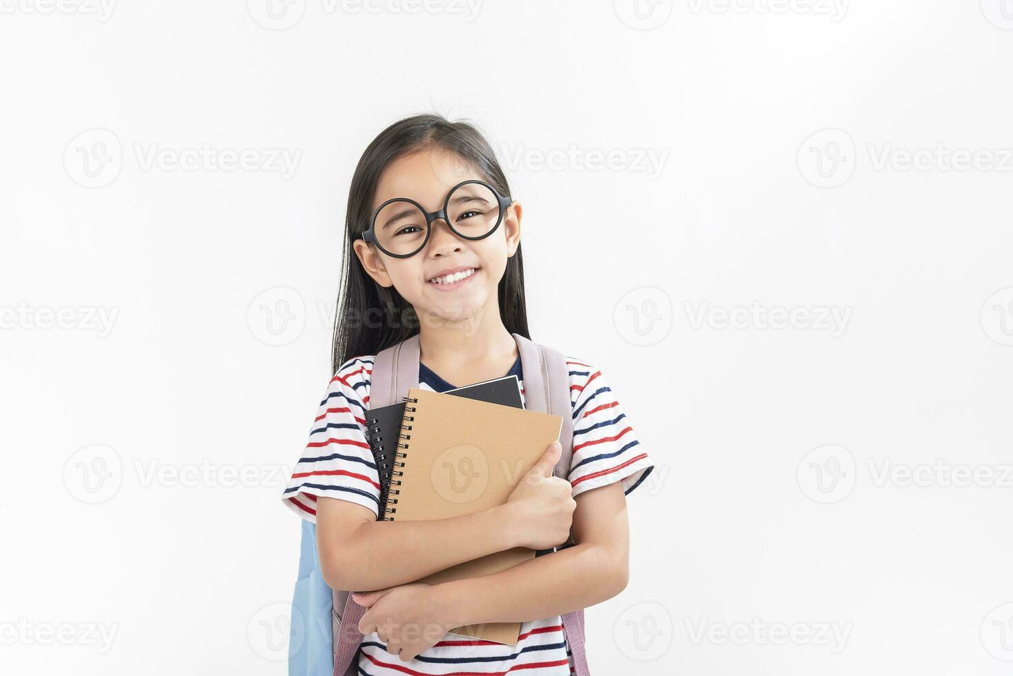 écolière étreindre livre portant sac à dos souriant isolé sur blanc Contexte photo