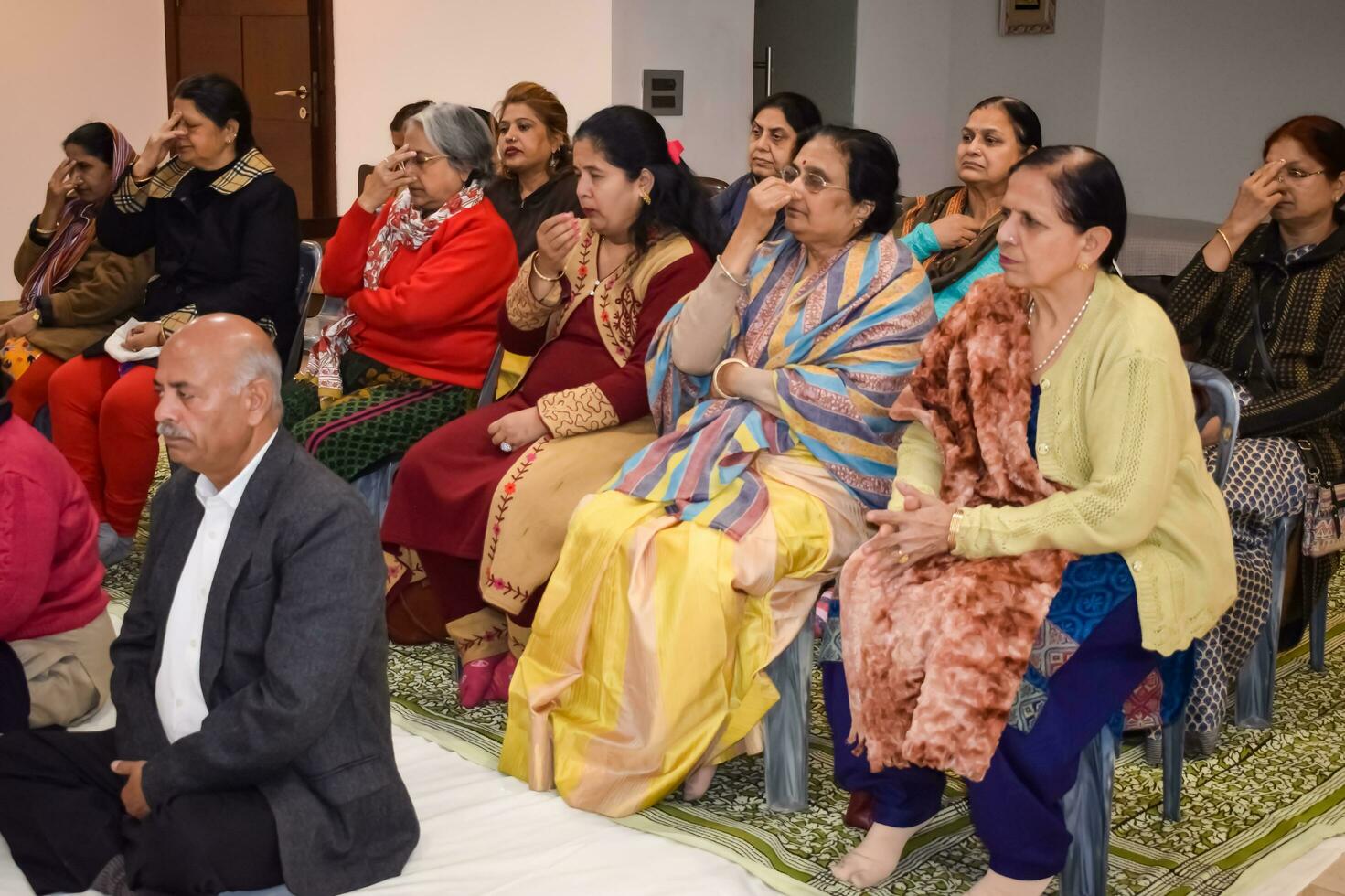 Nouveau Delhi, Inde, mai 31 2023 - groupe yoga exercice classe pour gens de différent âge dans yoga institut, international yoga jour, gros groupe de adultes assister une yoga classe à yoga art de vivant centre photo