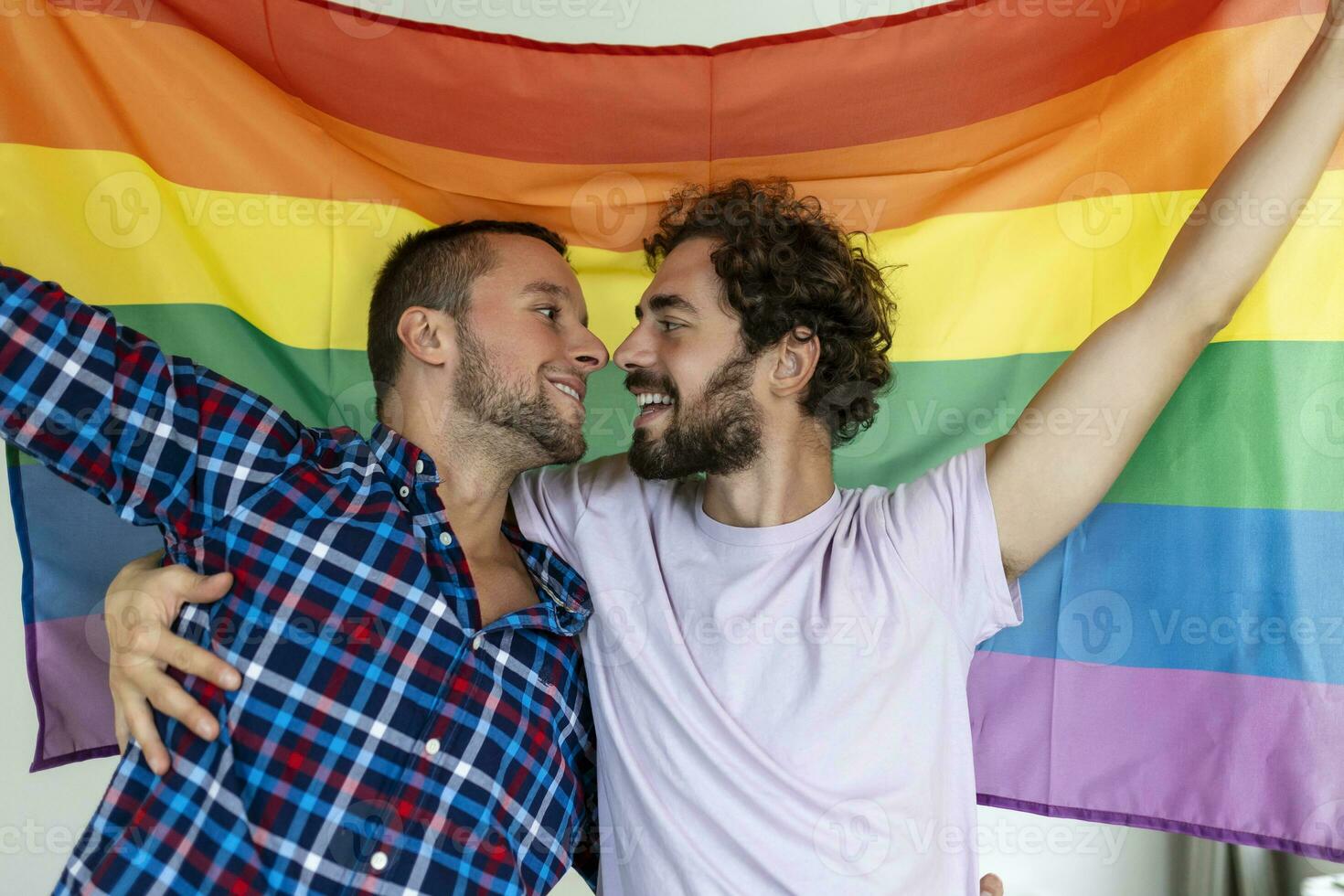 deux Jeune gay les amoureux embrasser chaque autre affectueusement. deux Jeune Masculin les amoureux permanent ensemble contre une fierté drapeau. affectueux Jeune gay couple partage une romantique moment ensemble. photo