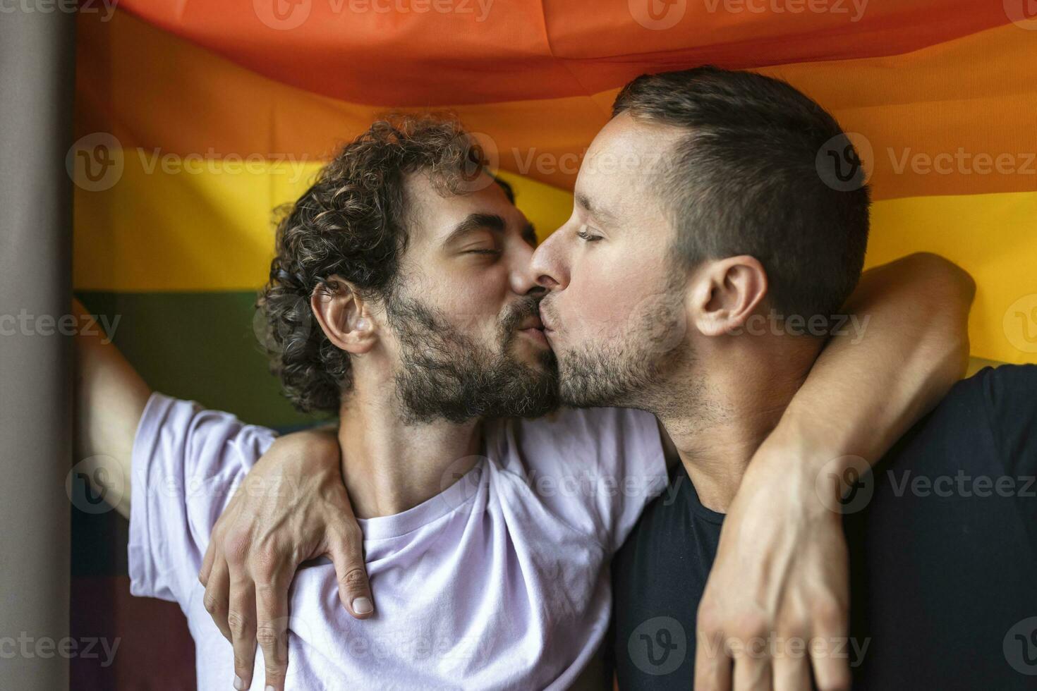 passionné gay couple fabrication en dehors avec lgbtq drapeau dans le Contexte. Jeune gay couple collage affectueusement à l'intérieur. photo