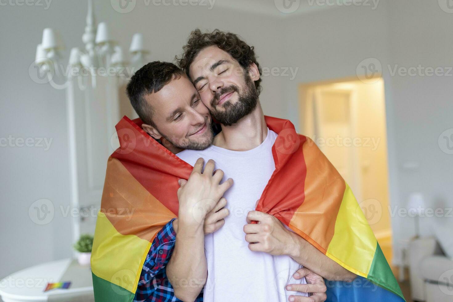 affectueux Masculin gay couple à l'intérieur. homme embrassement le sien copain de derrière à maison. gay couple célébrer fierté mois photo