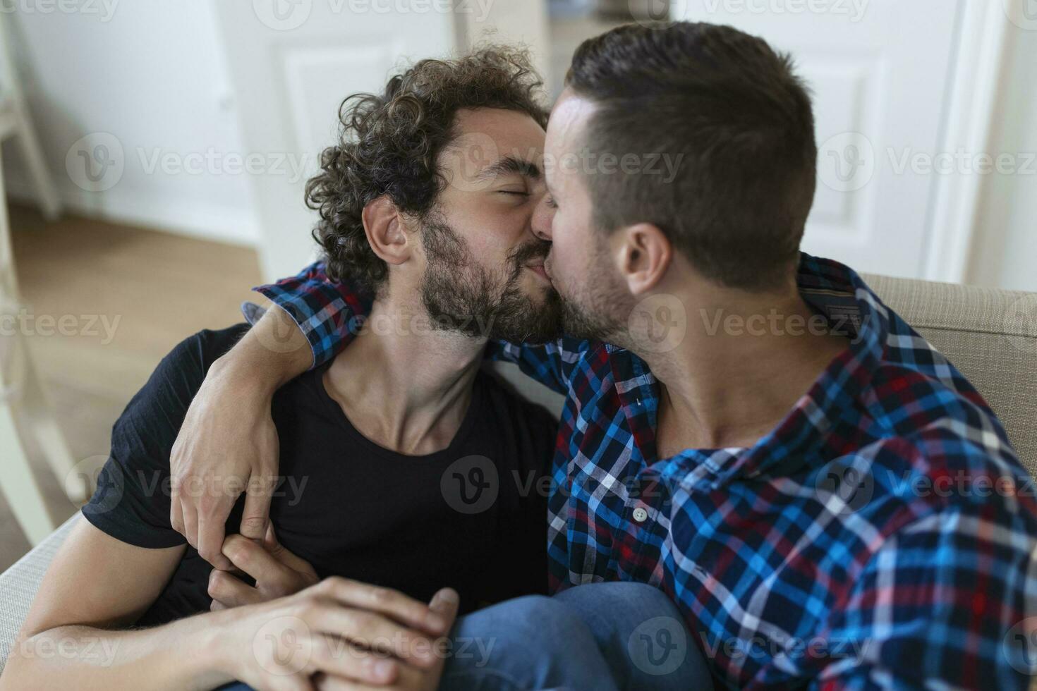 de bonne humeur Jeune gay couple séance ensemble. deux affectueux Masculin les amoureux souriant gaiement tandis que embrassement chaque autre. Jeune gay coupe étant romantique. photo