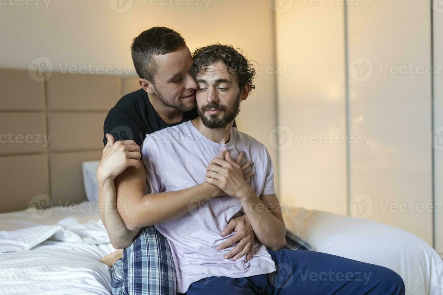 content gay couple mensonge vers le bas sur le lit à maison, étreindre et flirt. lgbt gay couple l'amour des moments bonheur concept photo