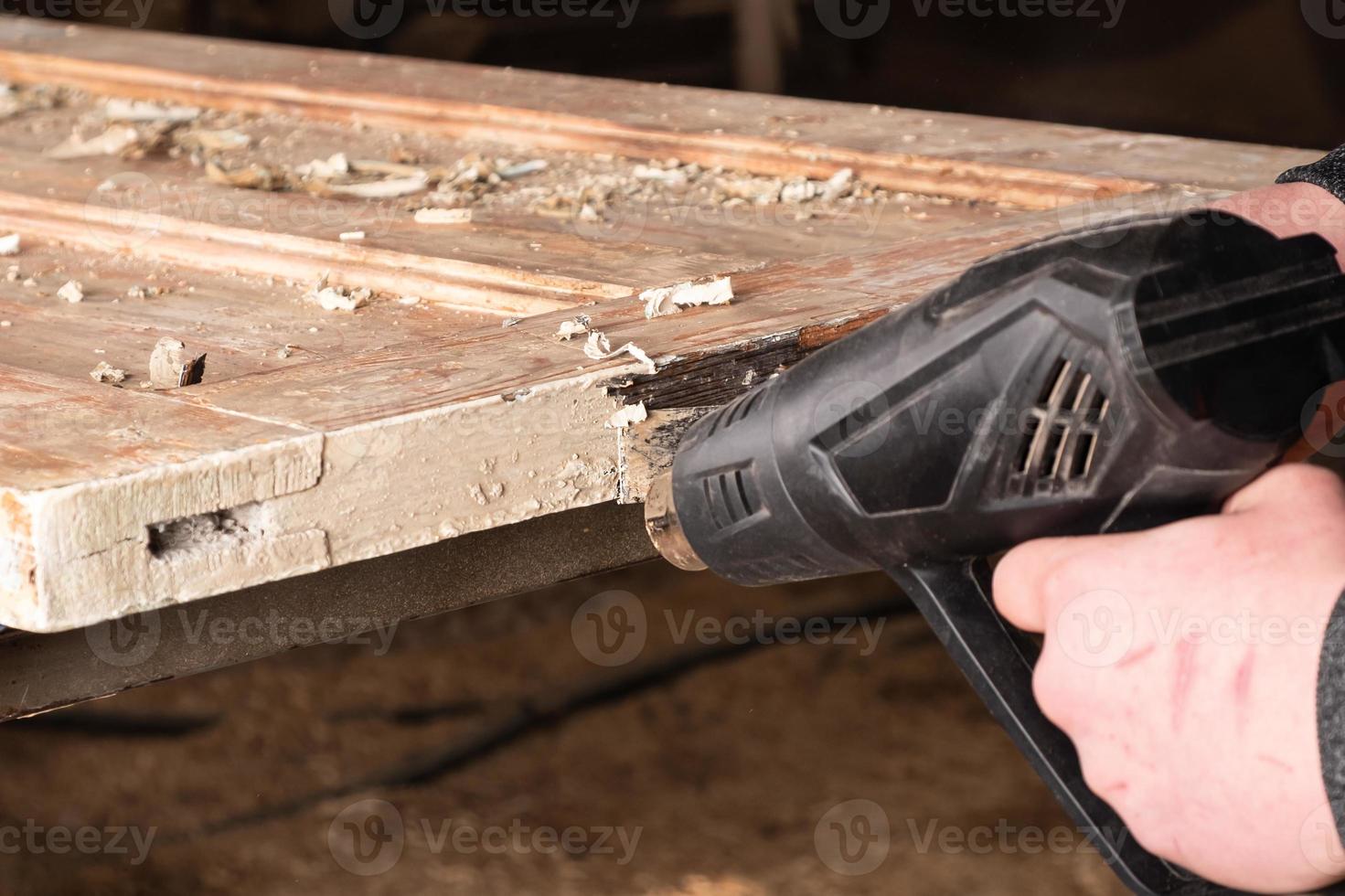 nettoyer les portes de la vieille peinture avec une spatule pour réchauffer la surface photo