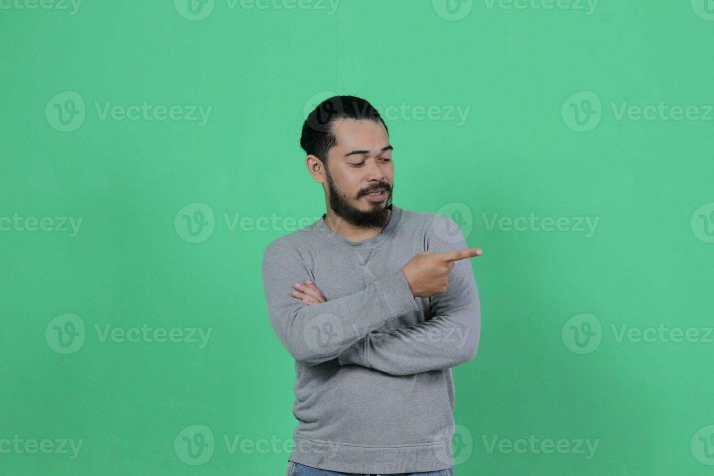barbu asiatique homme pose portant une gris chemise contre une vert Contexte photo