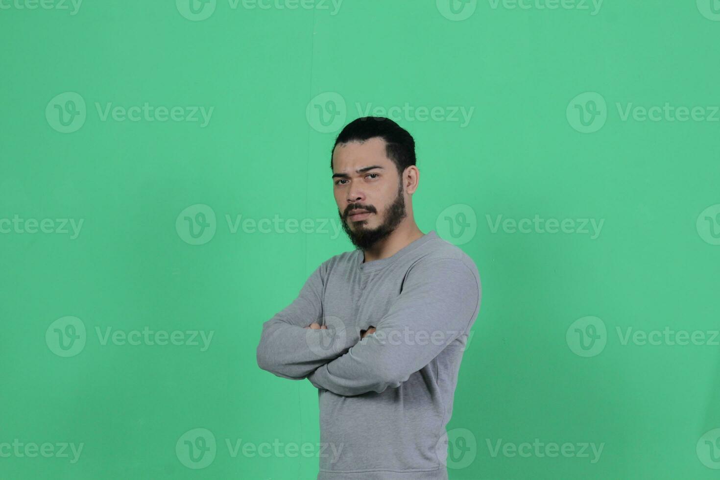 barbu asiatique homme pose portant une gris chemise contre une vert Contexte photo