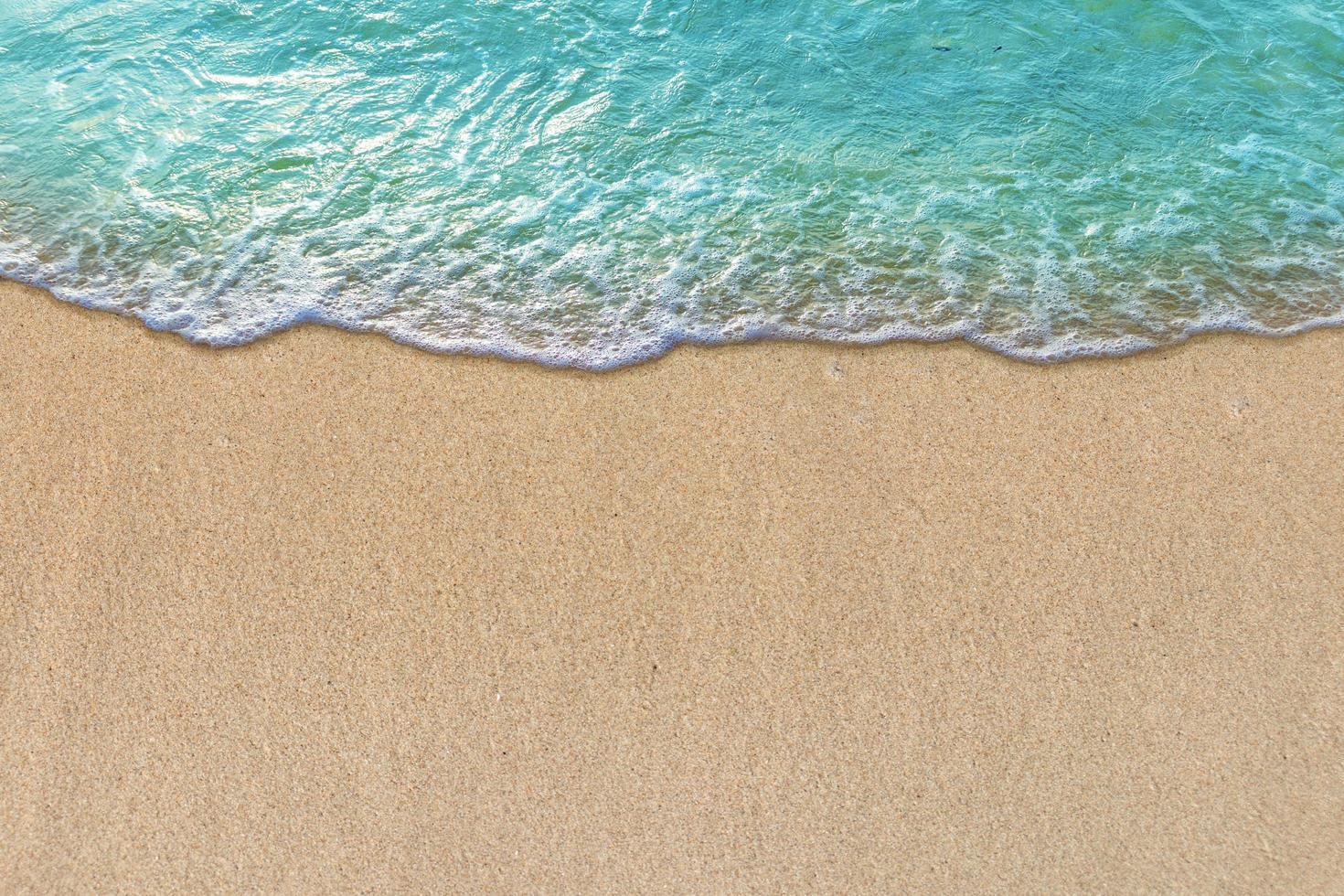 Été avec vague turquoise dans les vagues douces de plage tropicale avec de la mousse de l'océan bleu sur la plage de sable photo