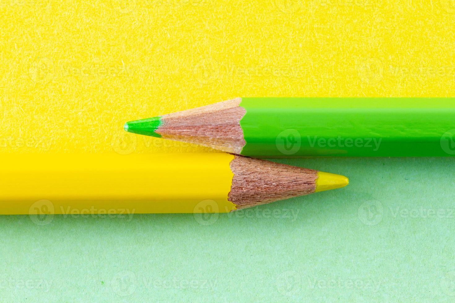 crayons de couleur sur papiers de couleur jaune et vert disposés horizontalement photo