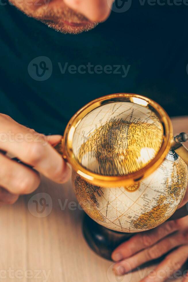 Masculin géographe examine une carte de Amérique - une grossissant verre dans le main de un archéologue voyageur photo