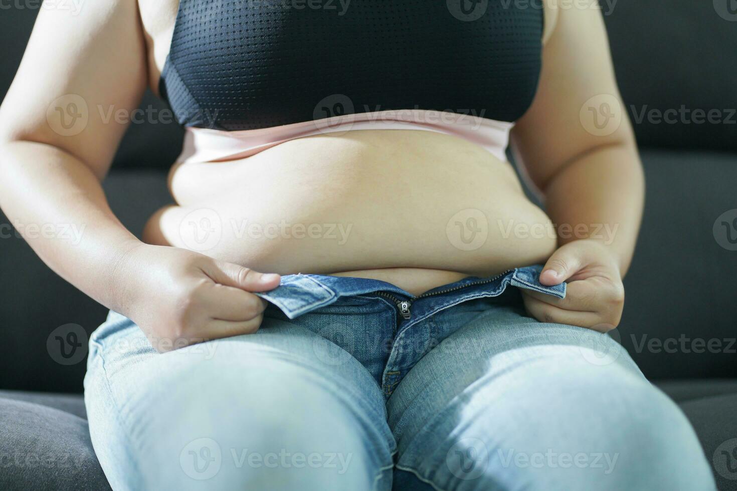 obèse femme avec graisse dérangé à propos sa ventre. en surpoids femme émouvant le sien graisse ventre et vouloir à perdre lester. graisse femme avec serré Vêtements inquiet à propos poids régime mode de vie concept photo