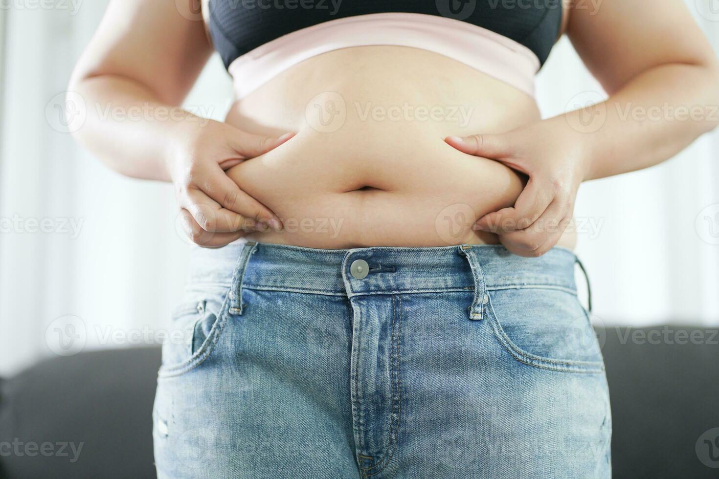 obèse femme avec graisse dérangé à propos sa ventre. en surpoids femme émouvant le sien graisse ventre et vouloir à perdre lester. graisse femme avec serré Vêtements inquiet à propos poids régime mode de vie concept photo