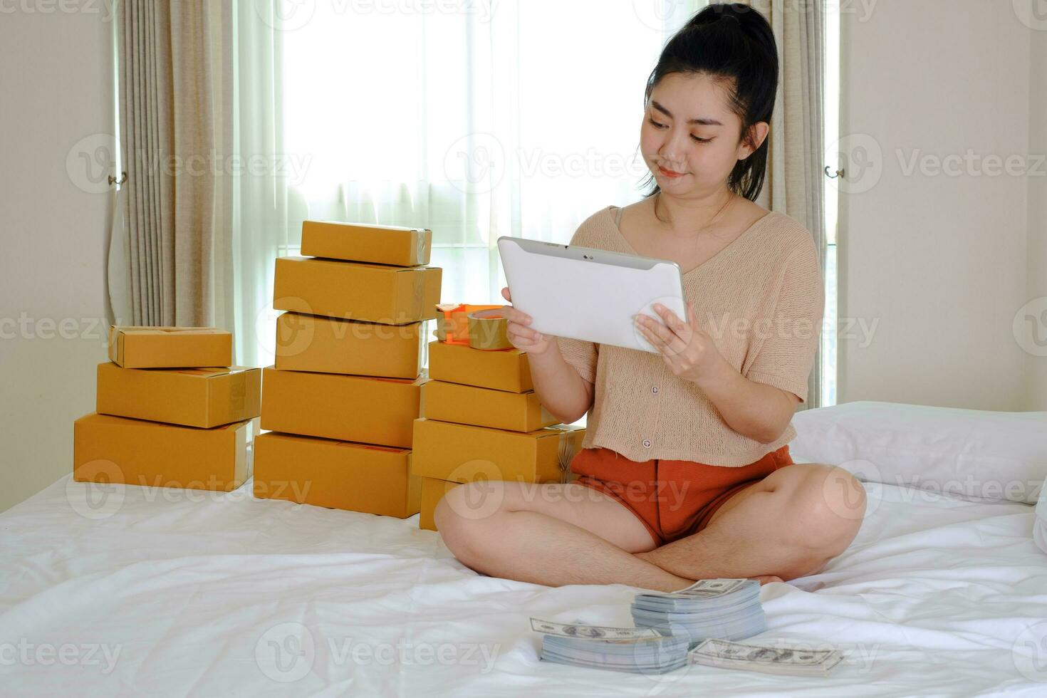 Asie jeune femme est assise sur le lit à l'aide d'un ordinateur portable dans sa chambre photo