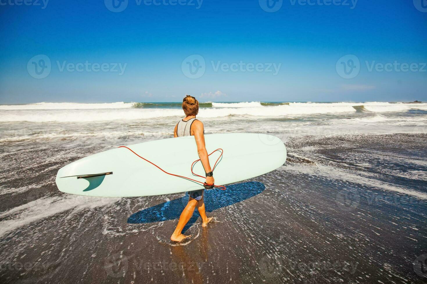 gars en marchant avec planche de surf sur une rive photo