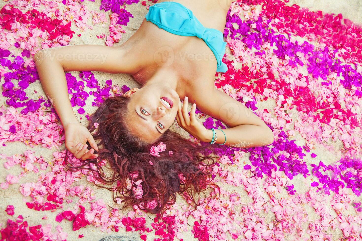 femme mensonge sur une fleur pétales sur une plage dans bali photo