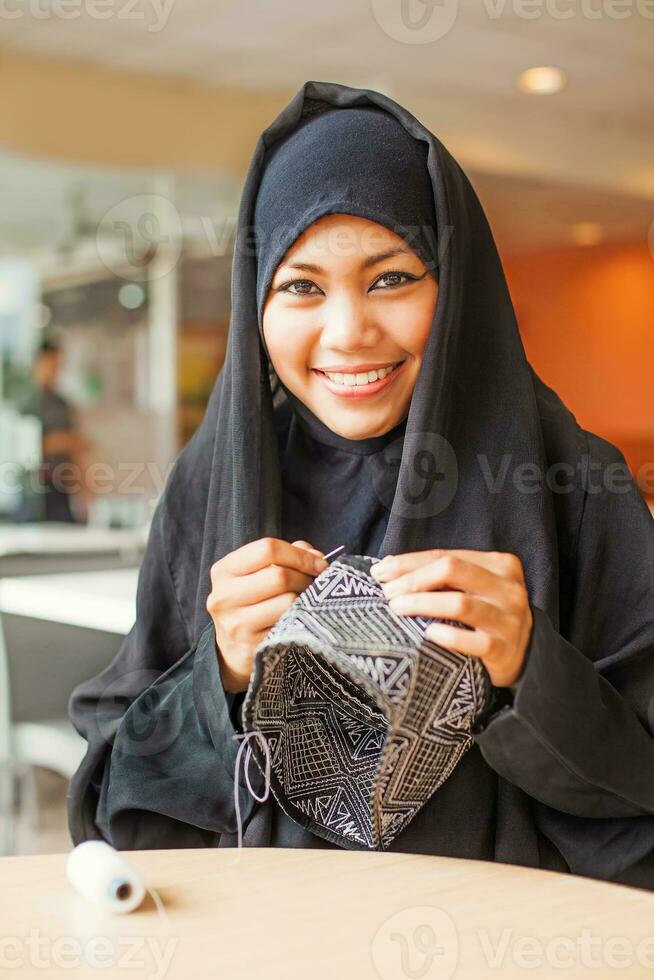 Jeune arabe souriant burka habillé femme couture une calotte photo