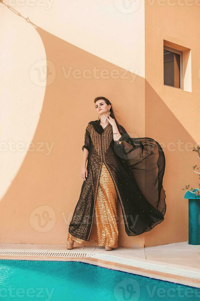 magnifique gracieux caucasien femme portant abaya avec le en tissu diffusion avec une vent photo