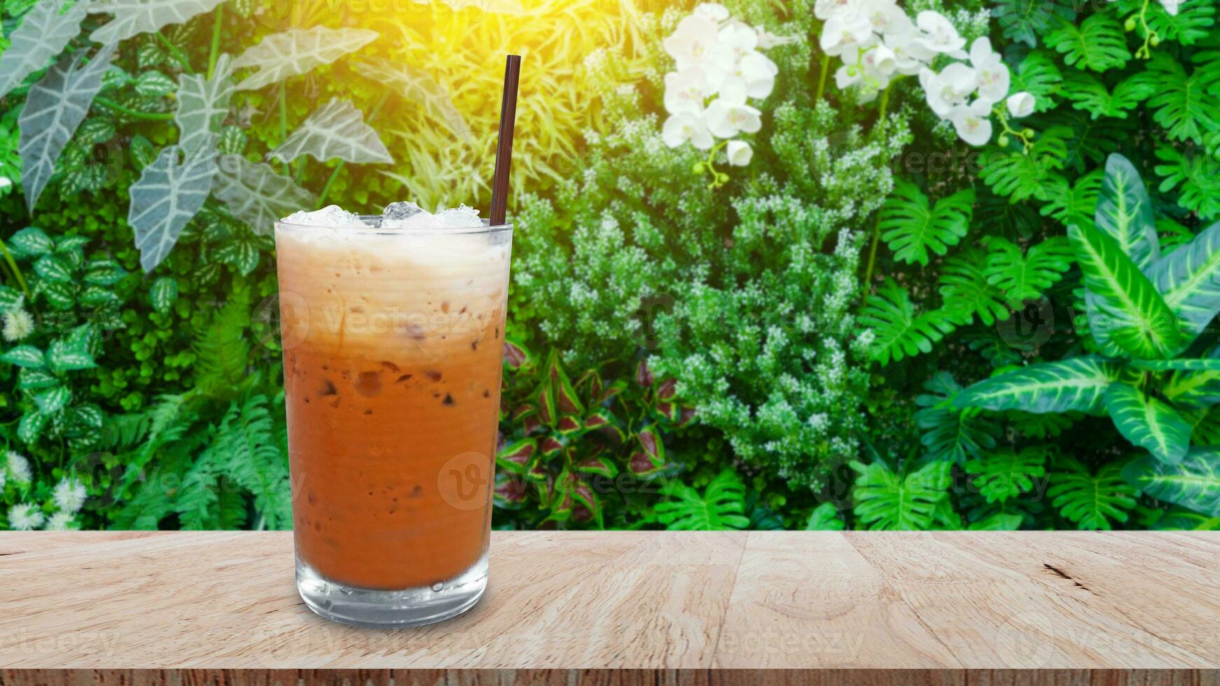 glacé thaïlandais Lait thé dans verre, Lait la glace thé, Cheddar est une traditionnel thaïlandais boisson sur en bois table avec la nature arrière-plan, été les boissons avec glacé photo