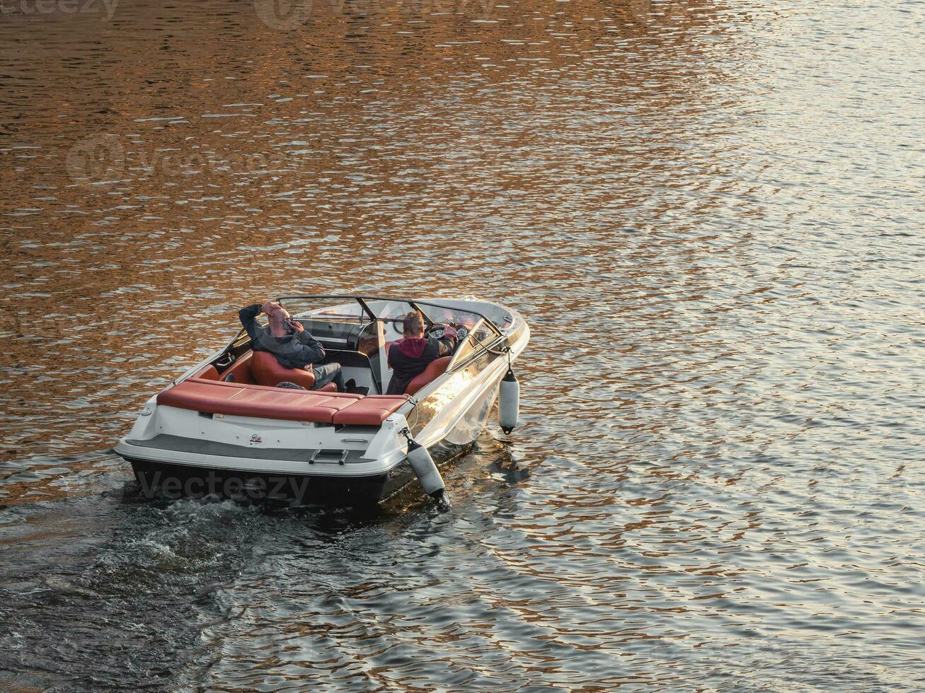 une luxe bateau à moteur des stands sur le l'eau à le coucher du soleil. se détendre dans une moteur bateau. photo