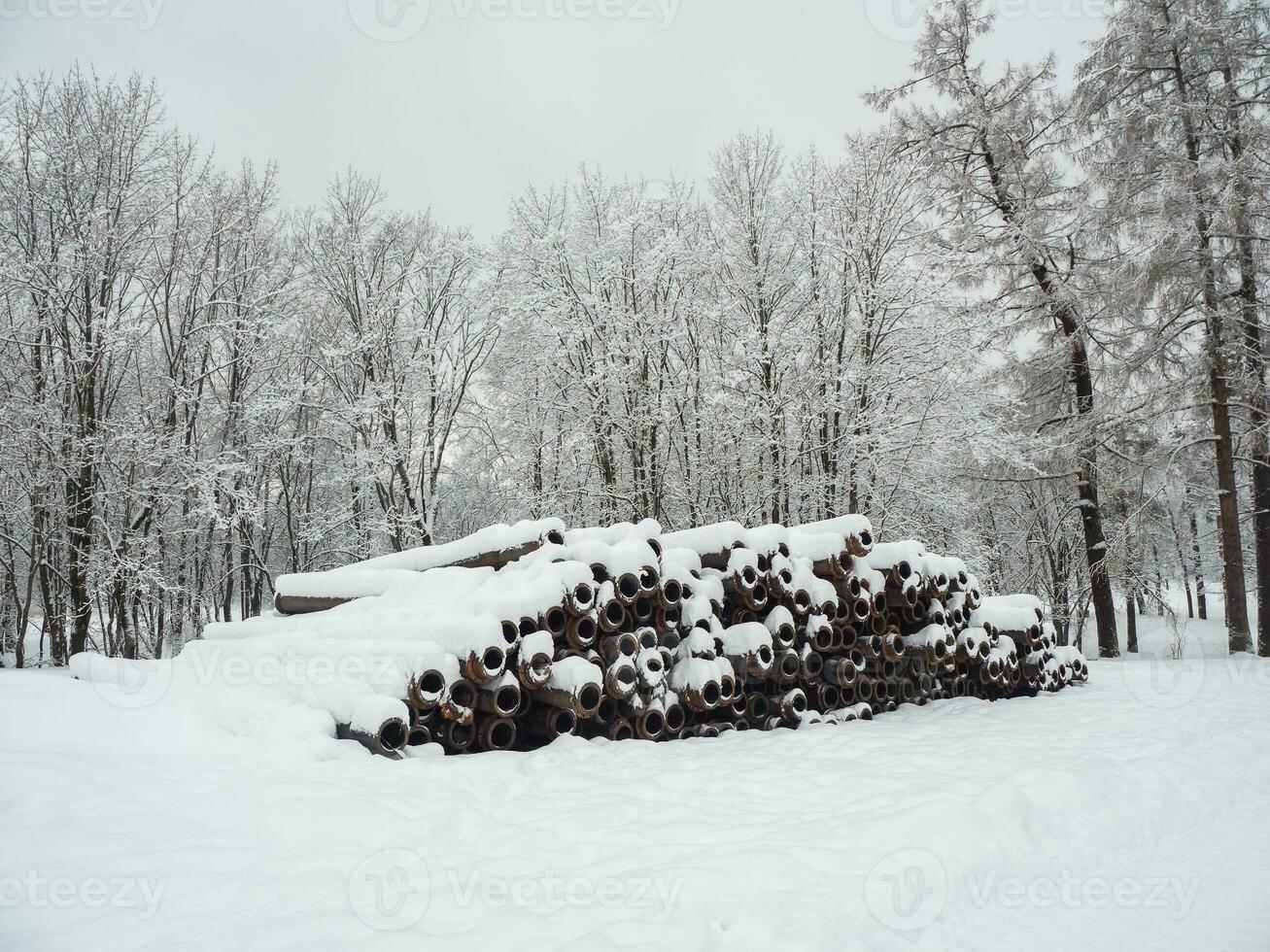 grand diamètre métal tuyaux pour pose communications, drainage systèmes et chauffage secteur en dessous de le route, empilés mensonge dans le ouvert air parmi congères en dessous de une couche de neige. photo