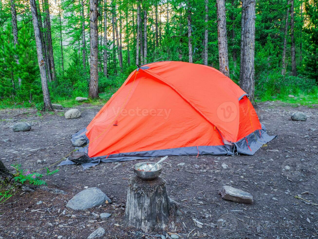 camping dans le Profond forêt. Orange tente dans une conifère Montagne forêt. paix et relaxation dans la nature. photo