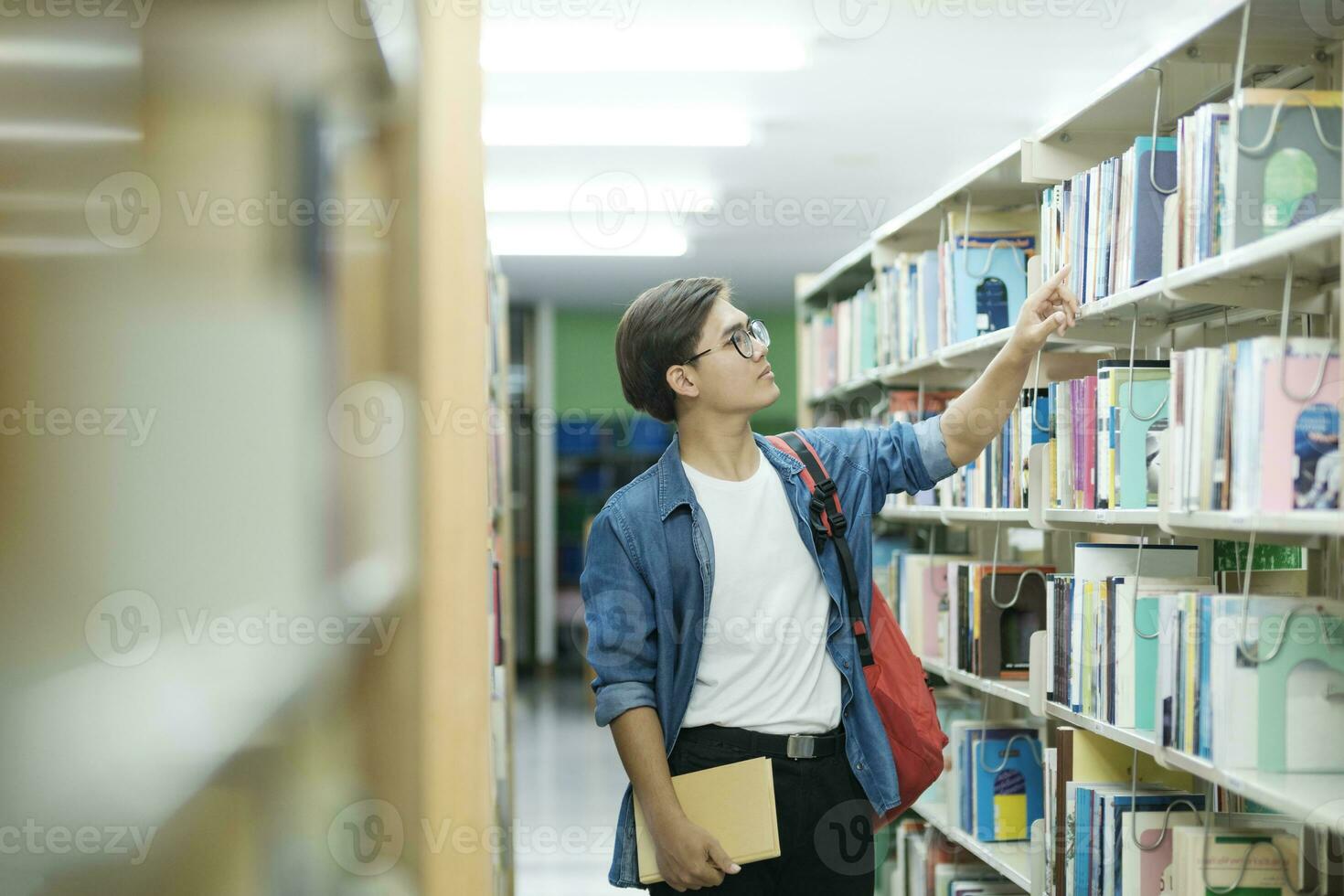 étudiant choisir et en train de lire livre à bibliothèque. photo