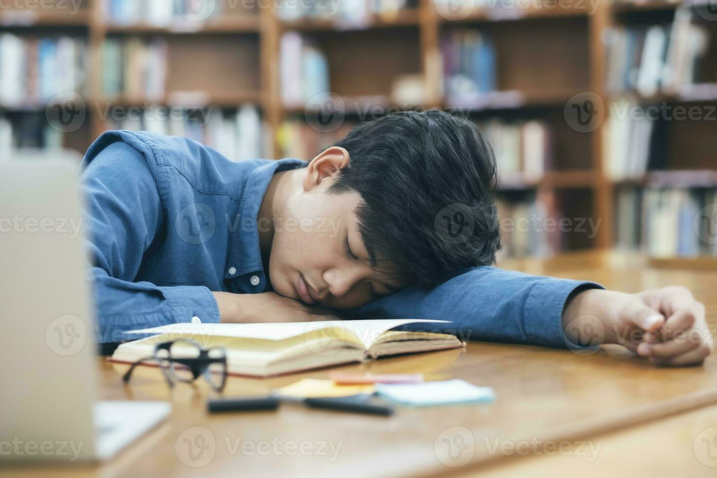 fatigué épuisé étudiant en train de dormir à bibliothèque. photo