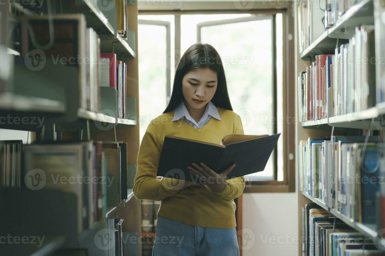 étudiant permanent et en train de lire livre à bibliothèque. photo