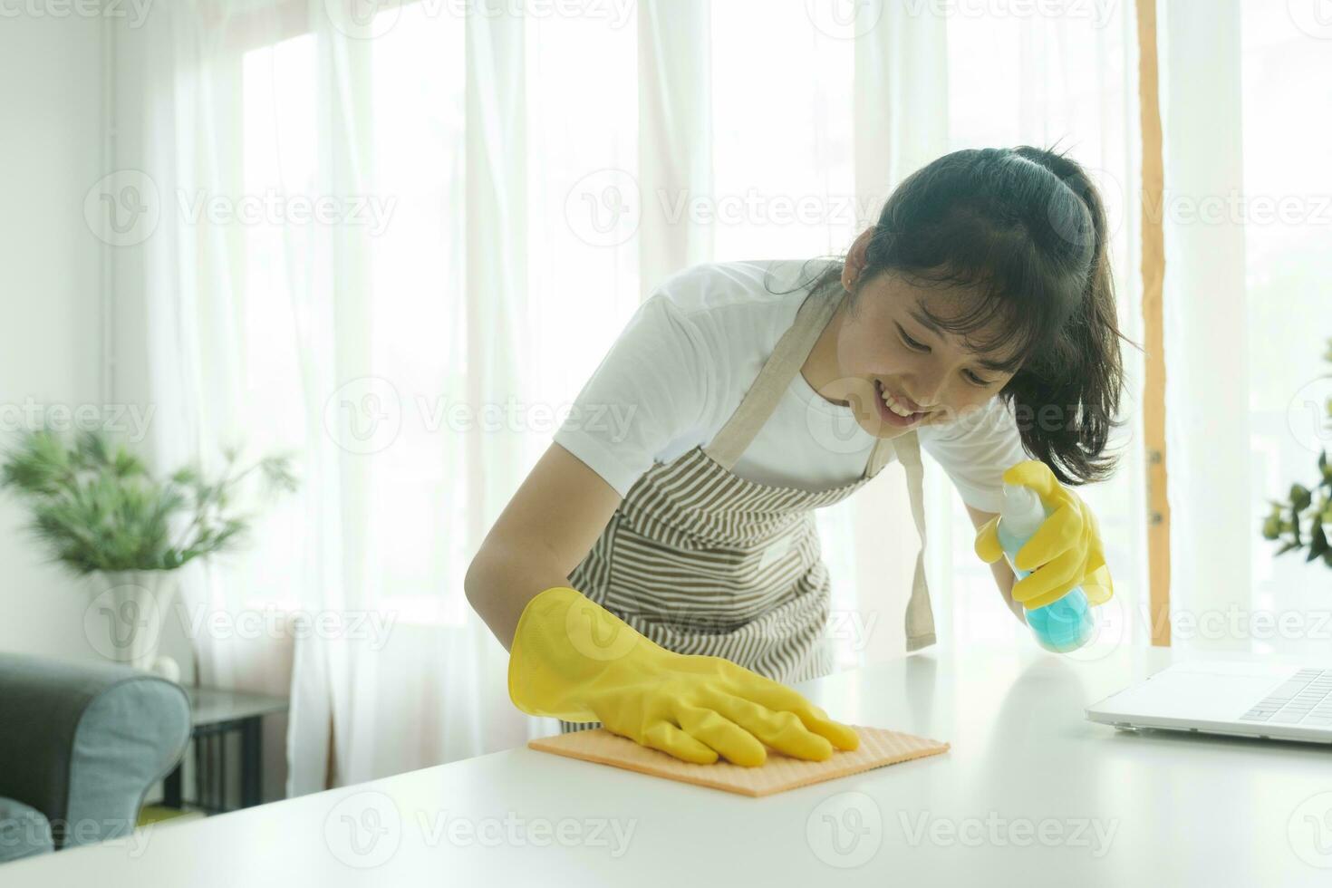 Jeune femme nettoyage table portant gants à maison. photo