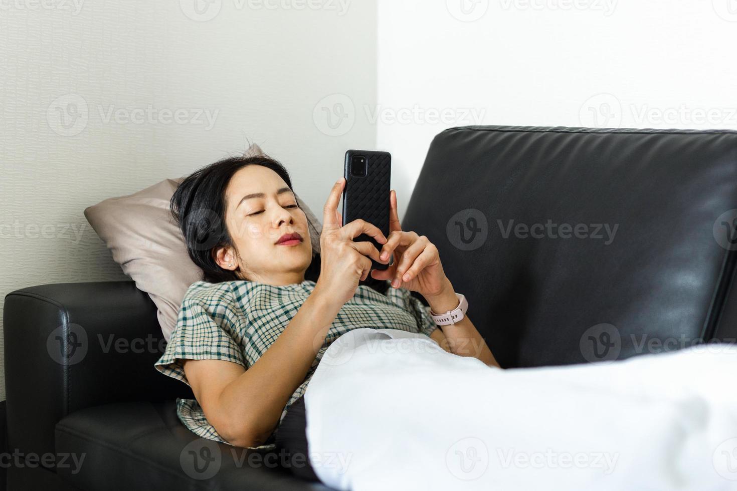 femme utilisant un téléphone intelligent en position couchée sur le concept de quarantaine de canapé photo