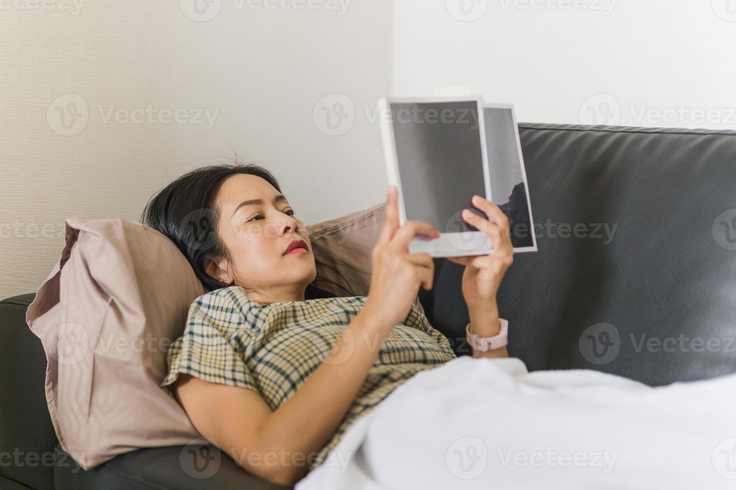 femme allongée sur le canapé et lisant un livre concept de quarantaine photo